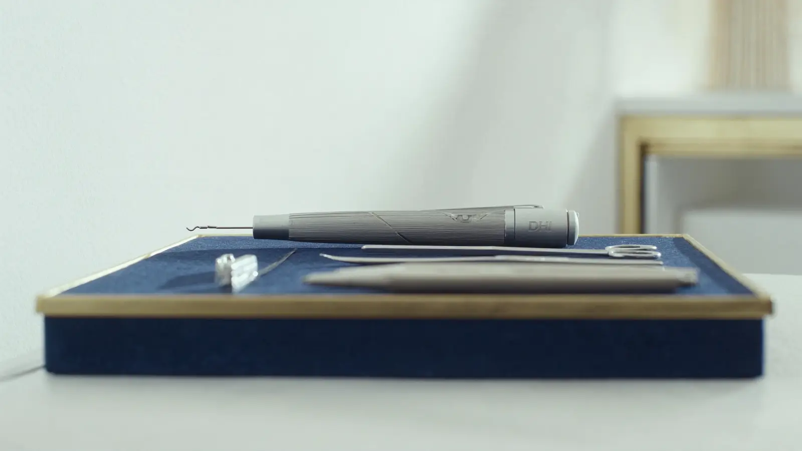 Realistic photographic close-up of a fine DHI implanter pen and sterile surgical tools arranged neatly on a navy tray with su